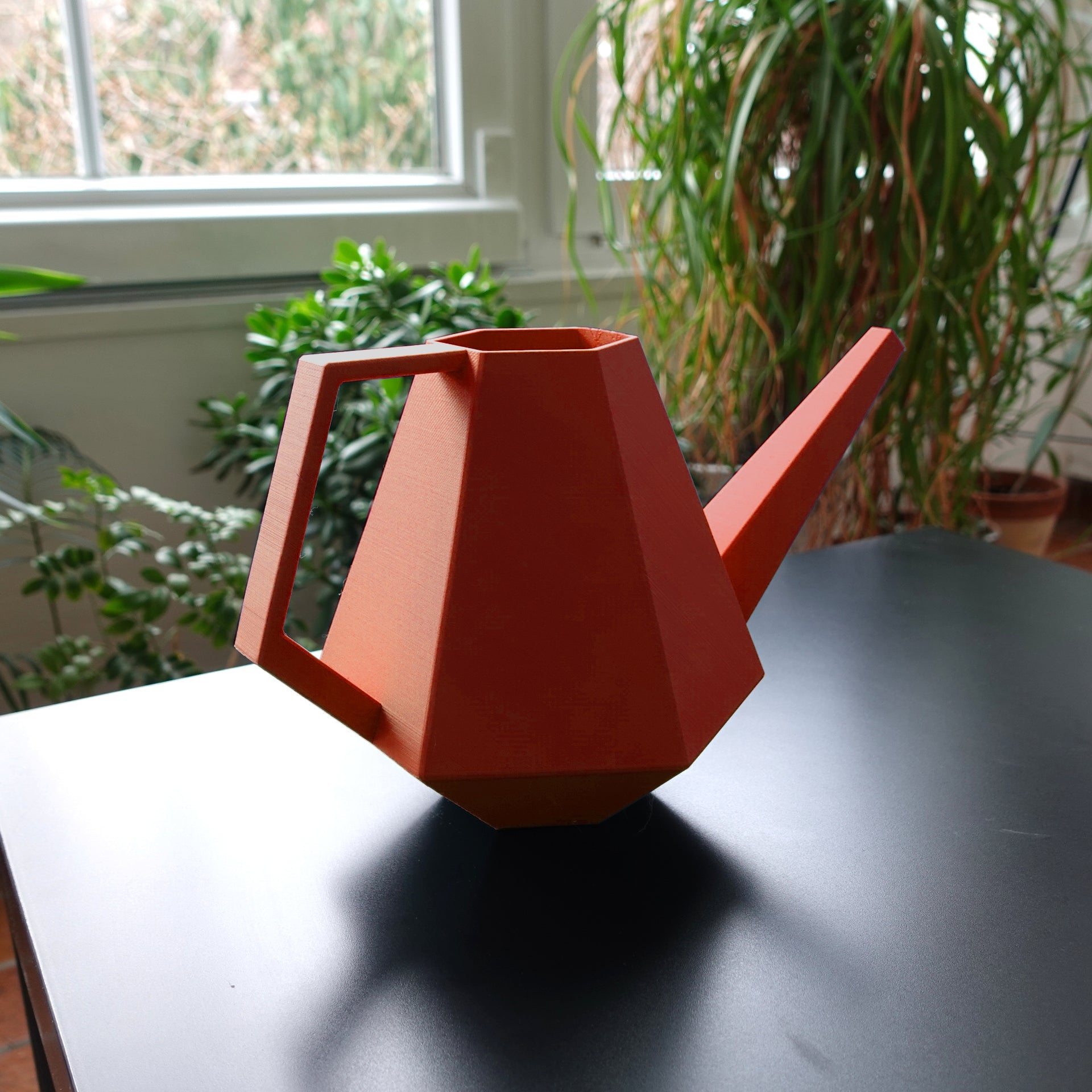 Realbild einer nachhaltigen Gießkanne aus recyceltem Verpackungsmaterial in der Farbe Terracotta / rot
